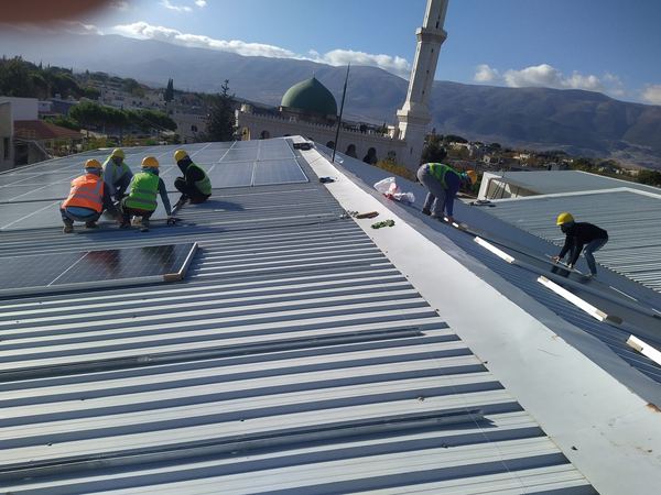 Our team installing panels on a metal roof, with helmets and harnesses